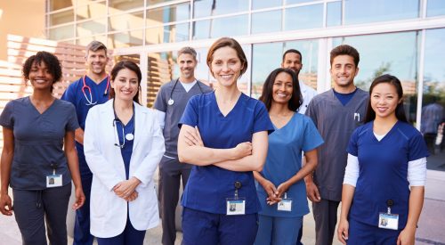 Team of healthcare workers with ID badges outside hospital